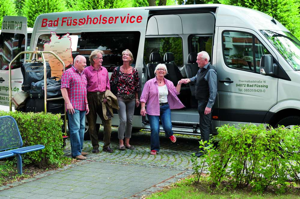 Mehrere Leute steigen bei Ankunft am Hotel Olympia aus dem Kleinbus aus.